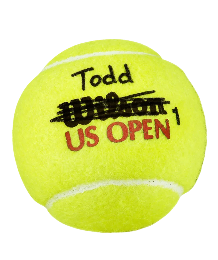 A Wilson US Open tennis ball with the Wilson logo struck through and the name Todd written above it in marker.